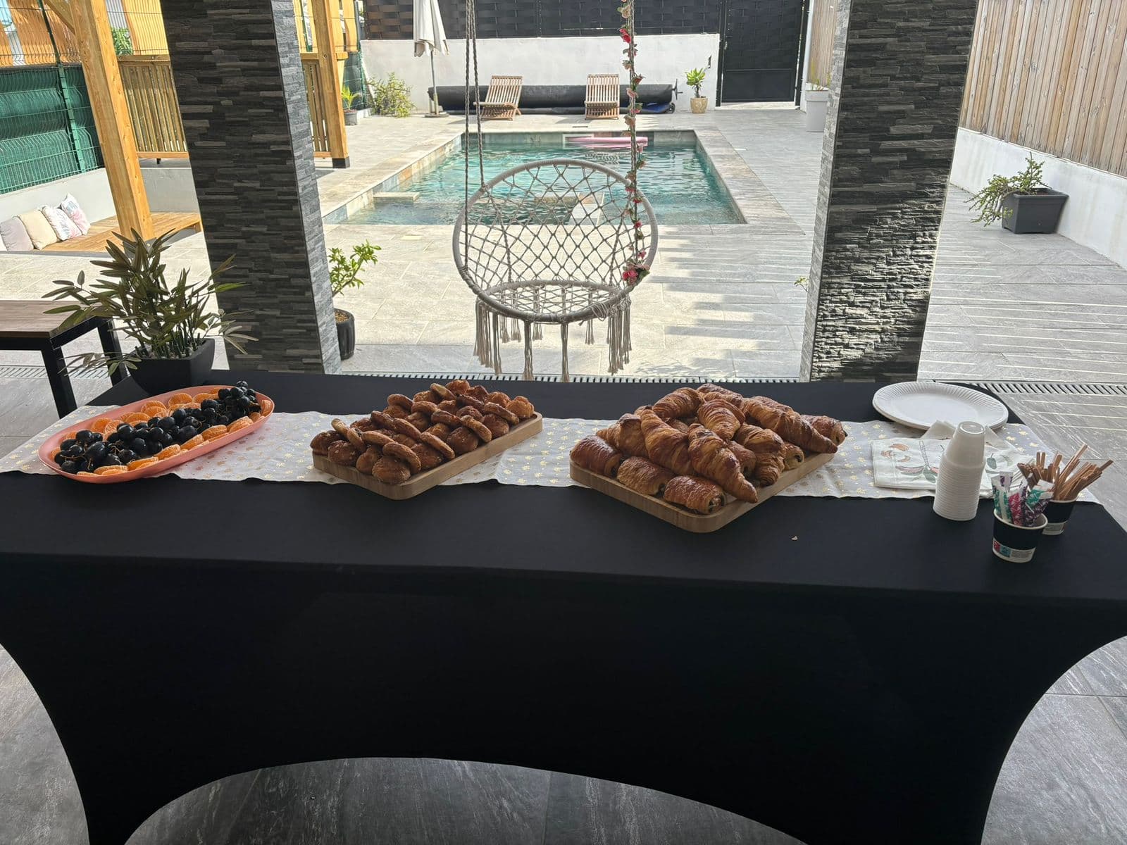 Table de brunch avec viennoiseries et fruits au bord de la piscine