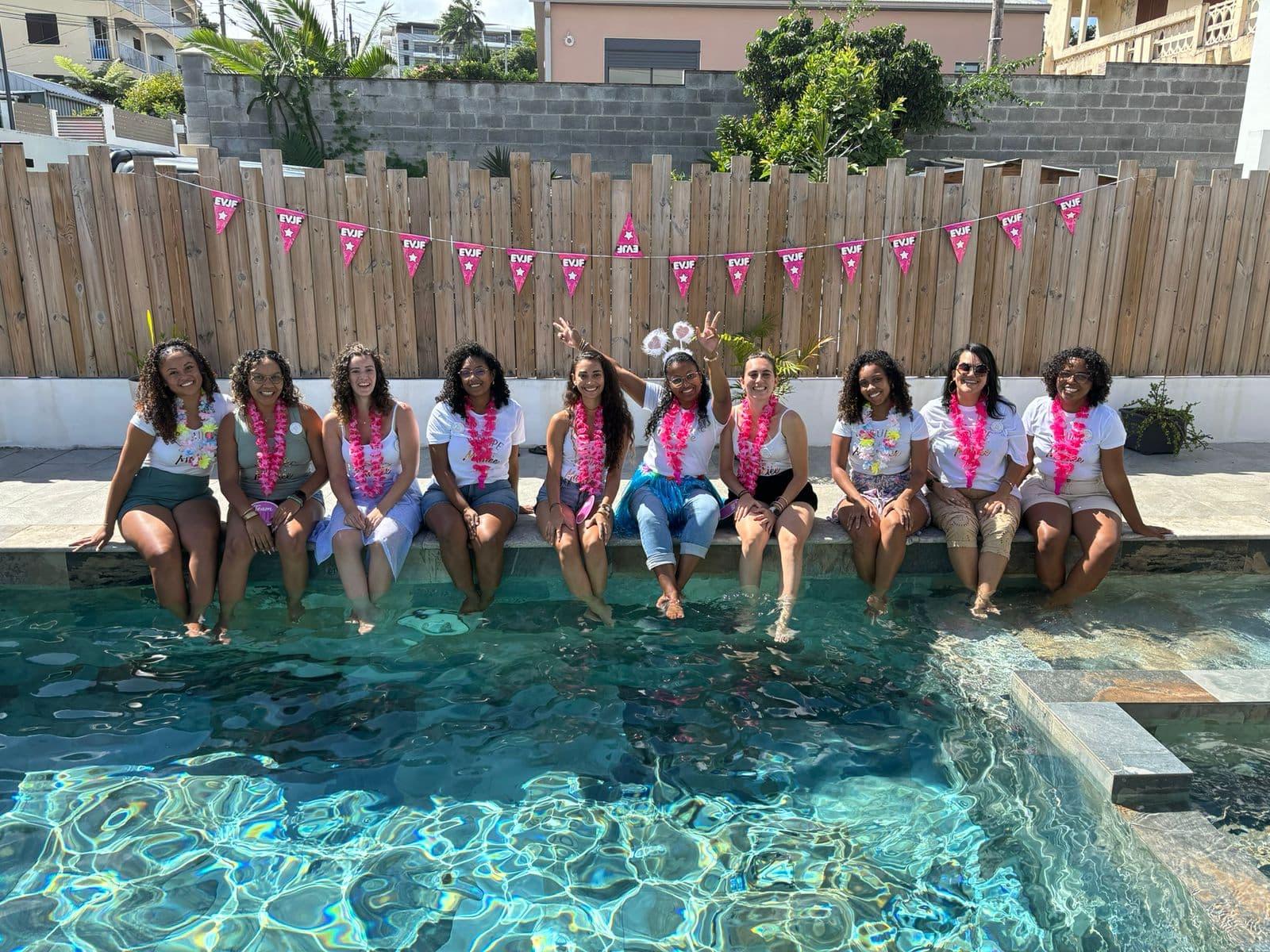 Groupe d'amies lors d'un EVJF avec colliers de fleurs au bord de la piscine